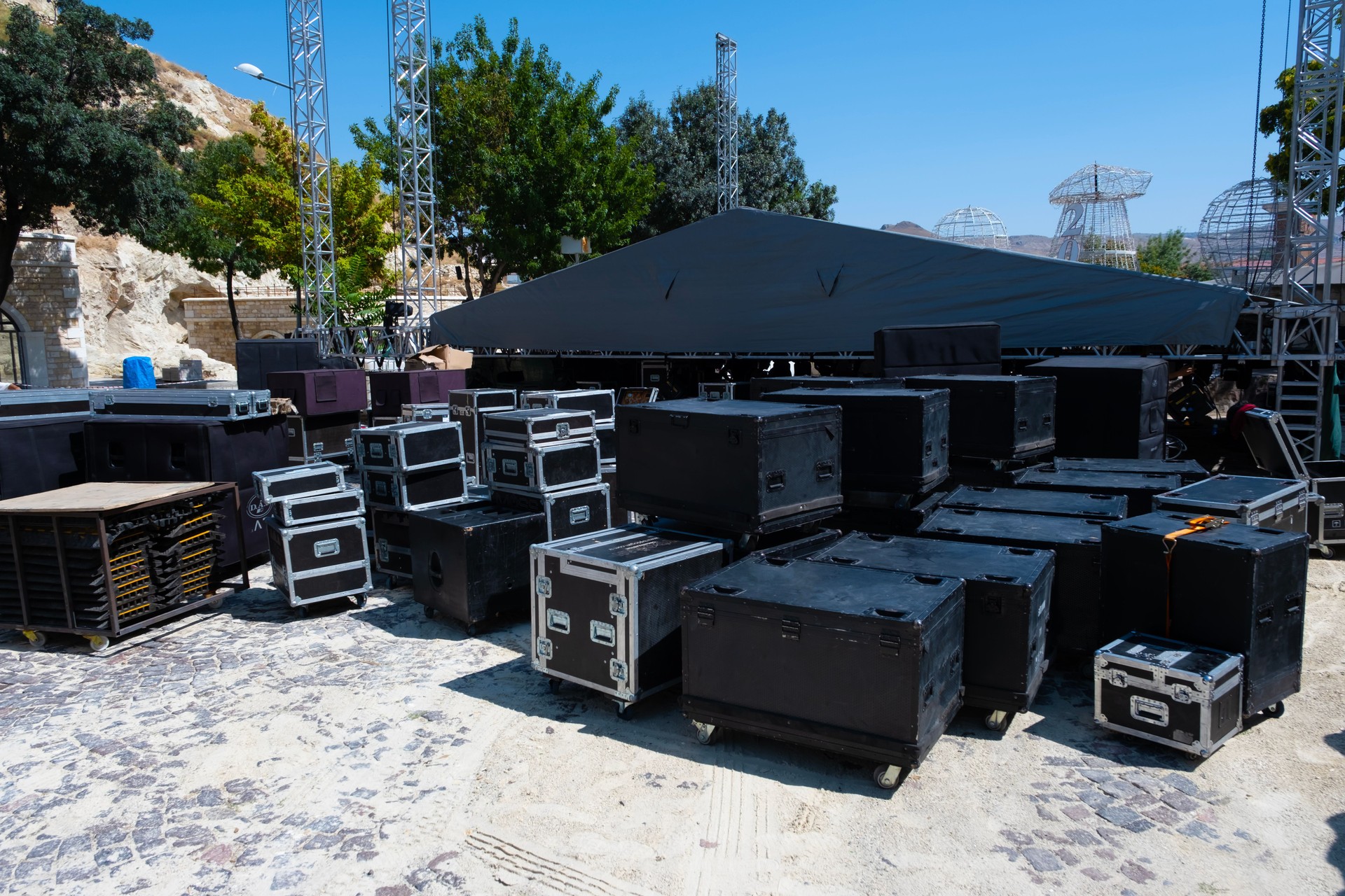 Stage background, architecture of building exterior. Installation of professional sound, light, video and stage equipment for a concert. Backstage area and tech zone with amplifiers, flight cases and radio microphones.